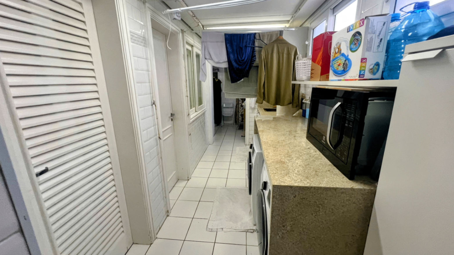 Lavanderia interna com bancada, armários e piso claro