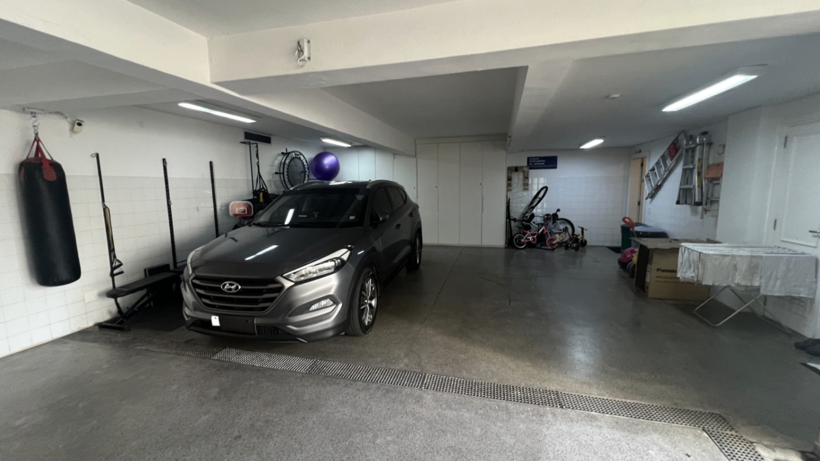 Garagem coberta com carro, saco de boxe e amplo pé-direito