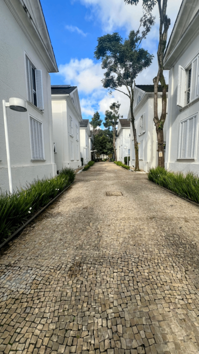 Alameda interna do condomínio com piso pé-de-moleque entre as casas