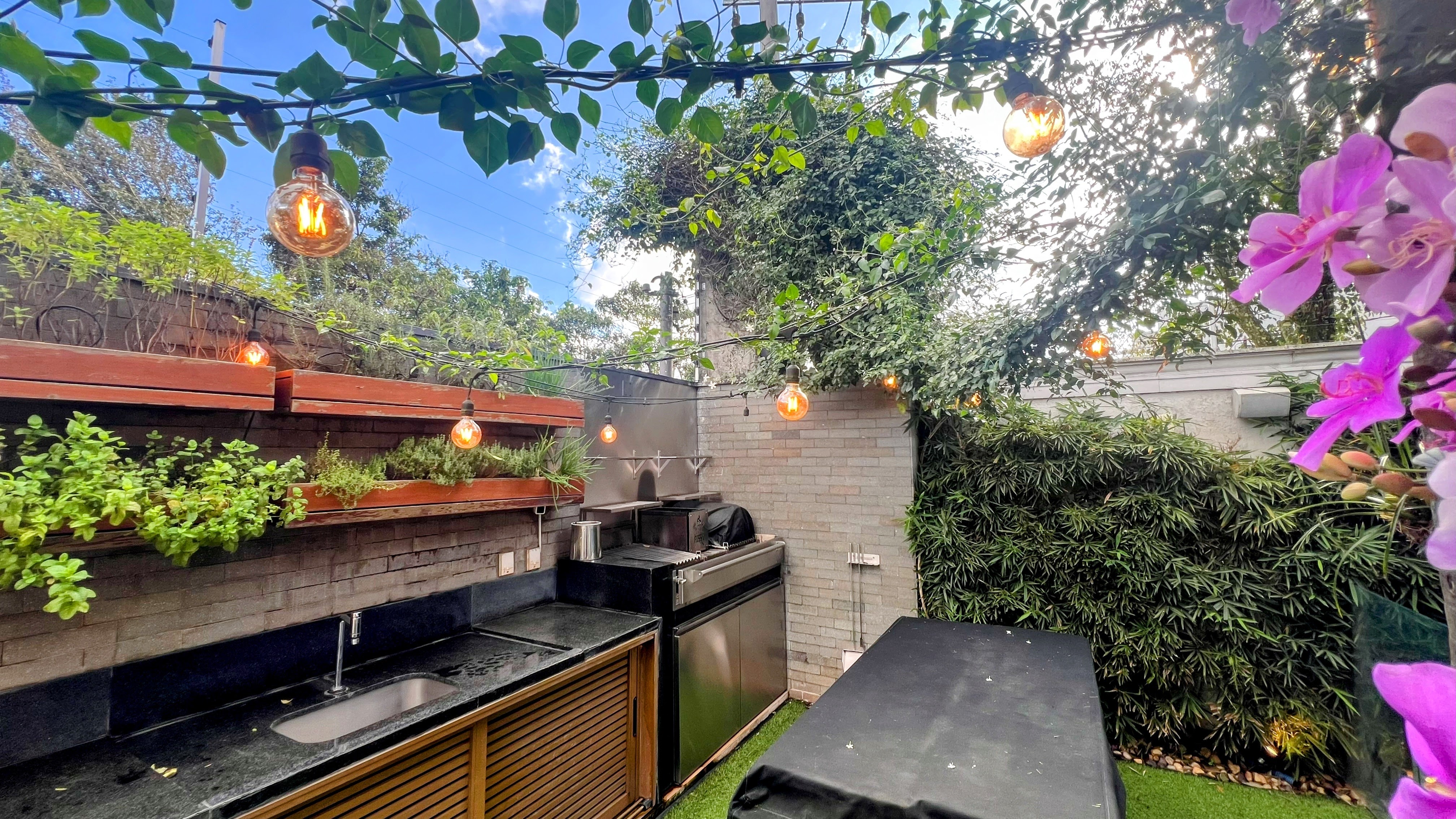 Área gourmet externa com bancada, parrilla e paisagismo