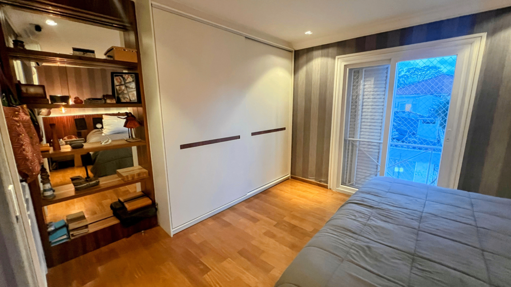 Closet com marcenaria branca, prateleiras abertas e acesso à varanda