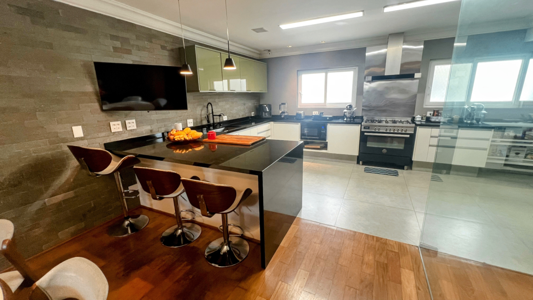 Cozinha ampla com ilha central, bancada em pedra e sala de refeições integrada