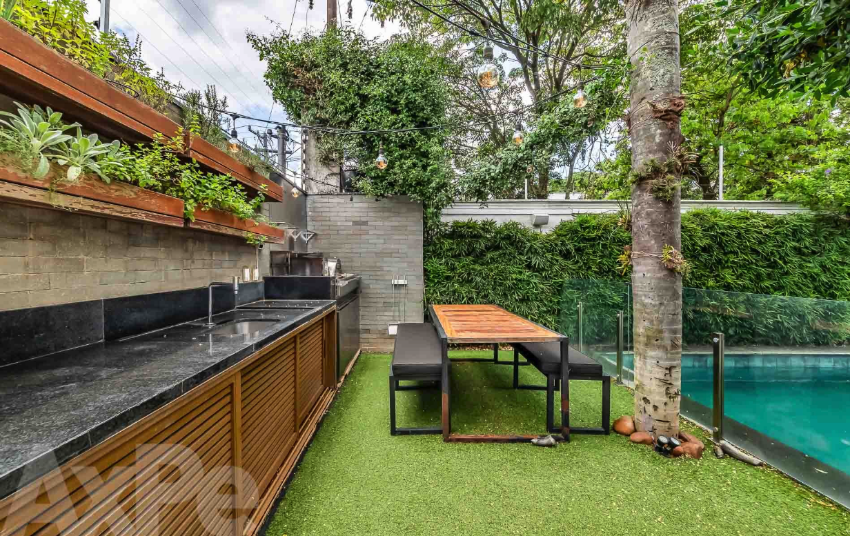 Área externa com bancada gourmet, jardim e piscina