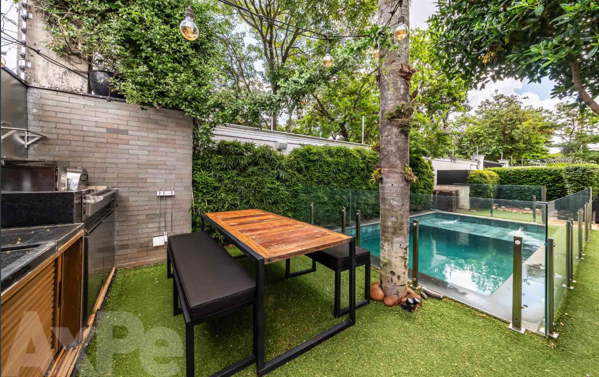 Área gourmet com parrilla e mesa de madeira ao lado da piscina