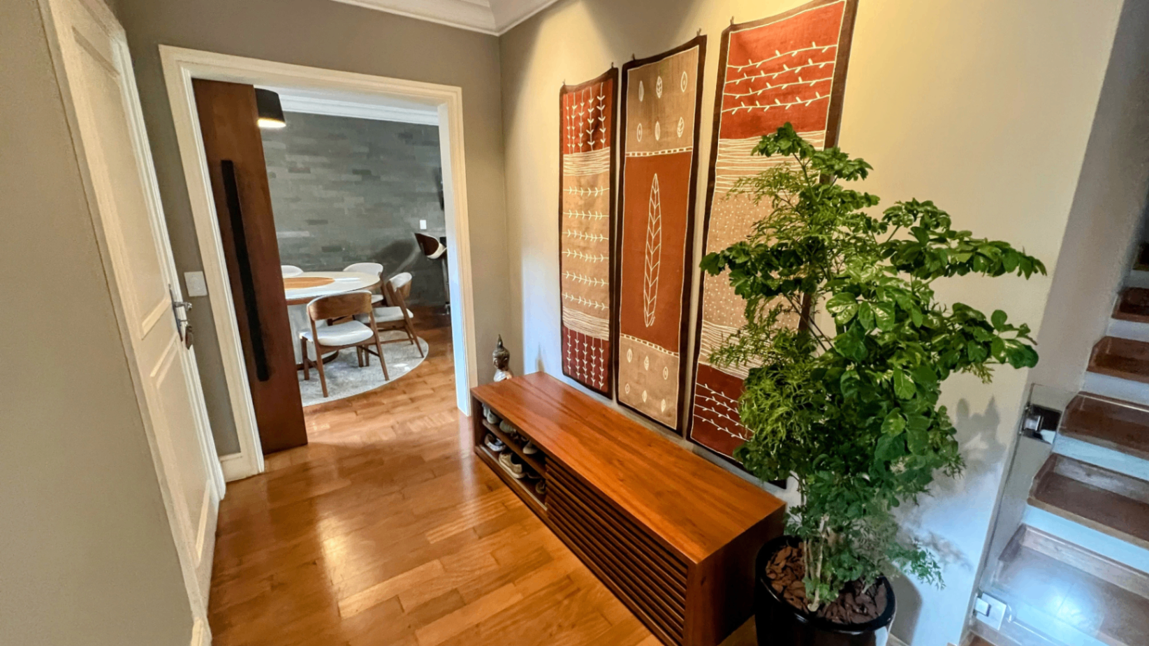 Hall interno com espelho de moldura, banco de madeira e planta