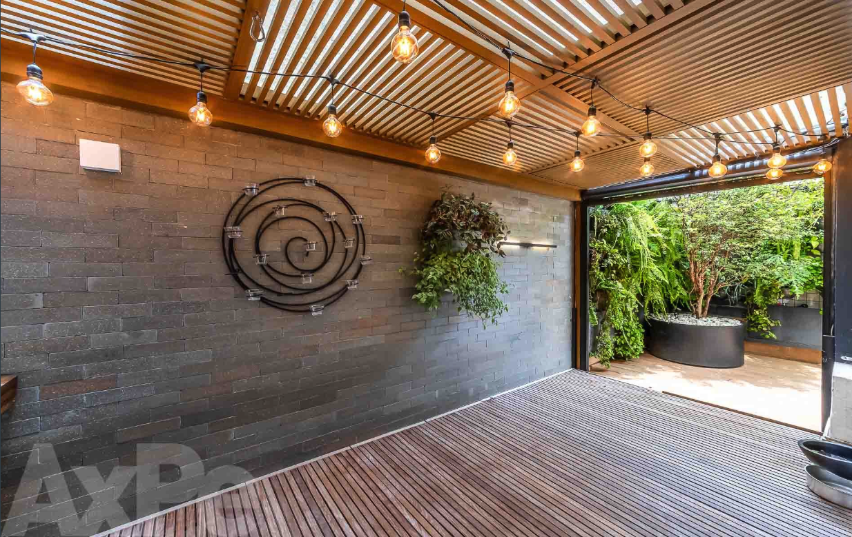 Área gourmet coberta com pergolado e iluminação decorativa