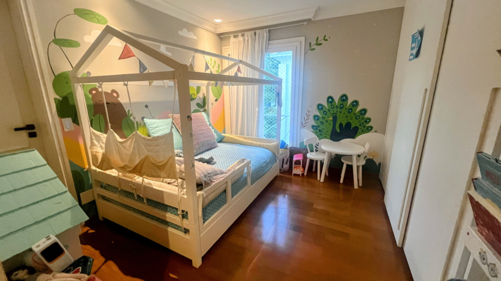 Quarto infantil com cama-casinha em madeira e mesa de brincar
